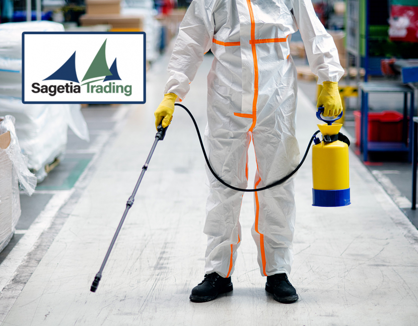 Front view portrait of man worker with protective mask and suit disinfecting industrial factory with spray gun.